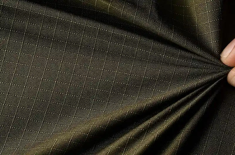 Close-up of dark green checkered fabric being pulled