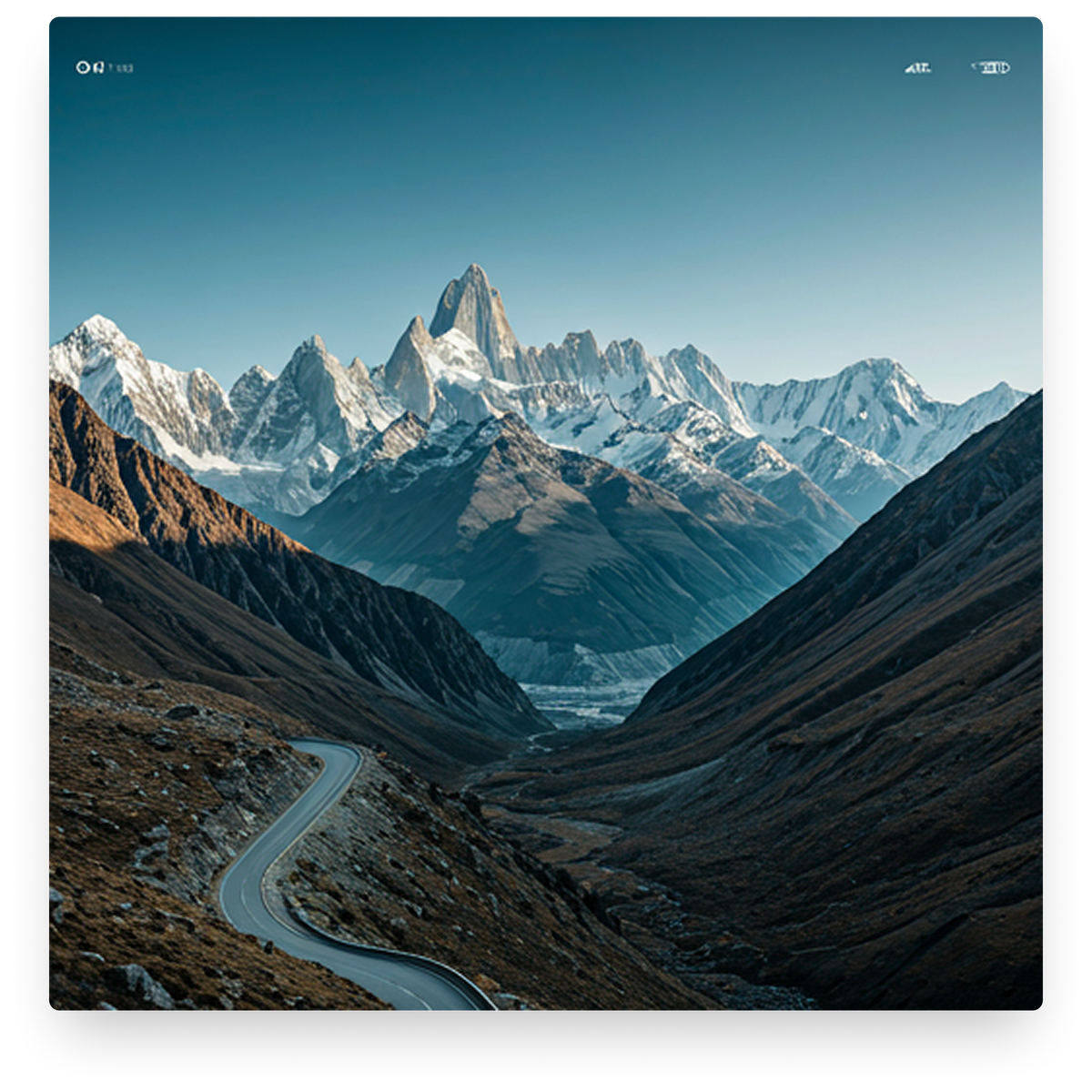 Winding road through a mountainous landscape with snow-capped peaks.
