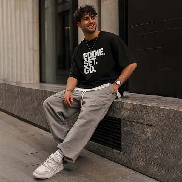 A man wearing a black graphic t-shirt with 'EDDIE. SET.